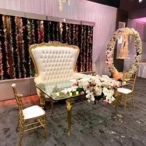 Luxurious wedding sweetheart table with gold trim, tufted white throne chair, floral arch, and candle décor at Macedonian Culture Center in Crown Point, Indiana