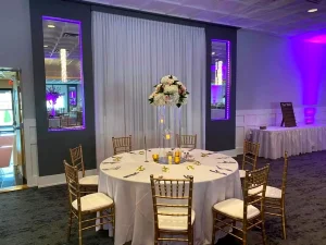 Elegant round table with gold chiavari chairs, floral centerpiece, and purple uplighting at Macedonian Culture Center in Crown Point, Indiana