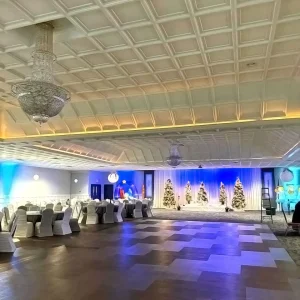 Winter-themed banquet hall with Christmas trees, blue uplighting, chandeliers, and dance floor at Macedonian Culture Center in Crown Point, Indiana